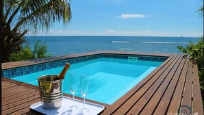 A wooden deck with a pool, a champagne bottle, and glasses. - South Point Villas (Cerf Island)