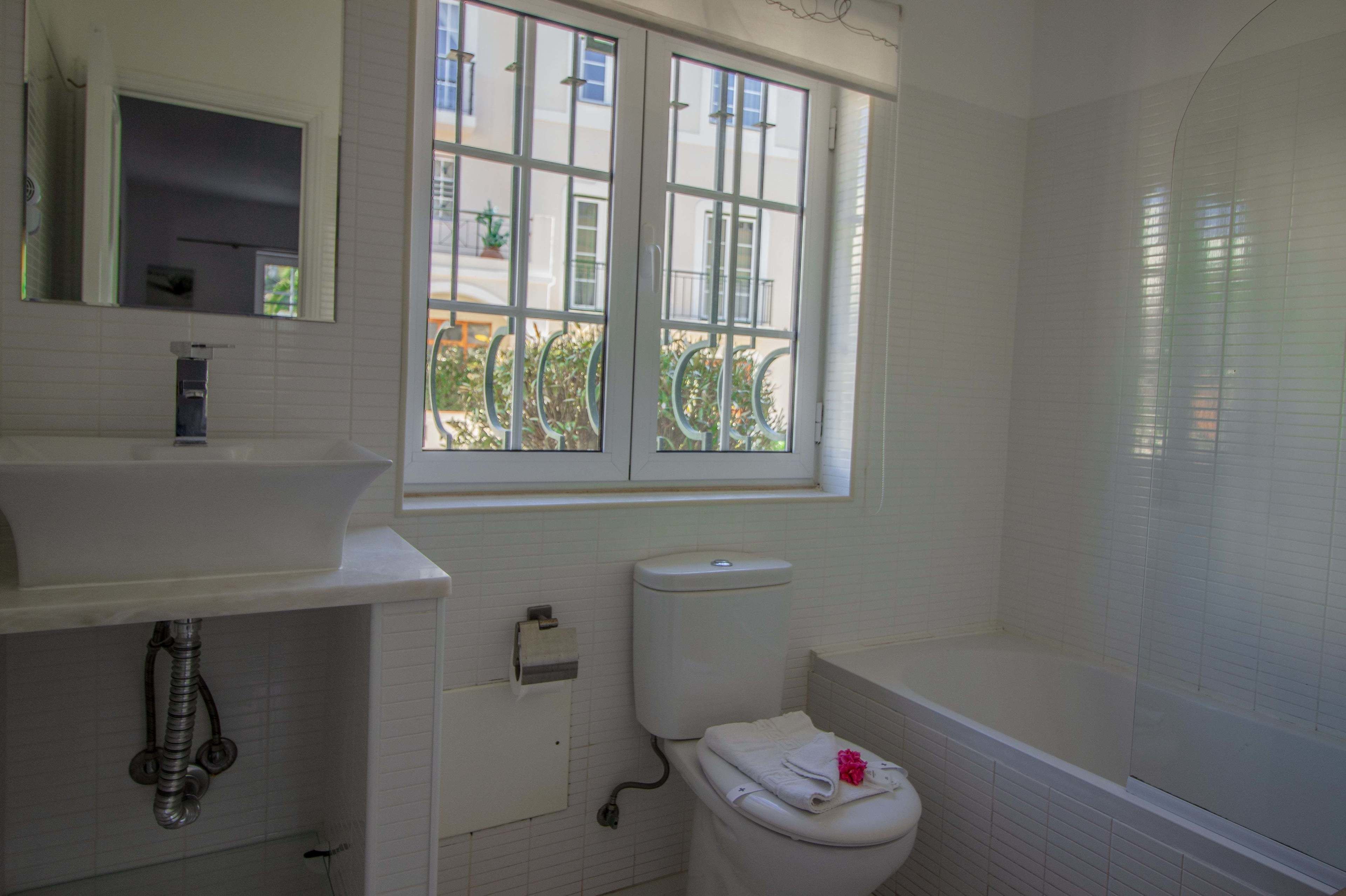 Een badkamer met toilet, wastafel en raam.