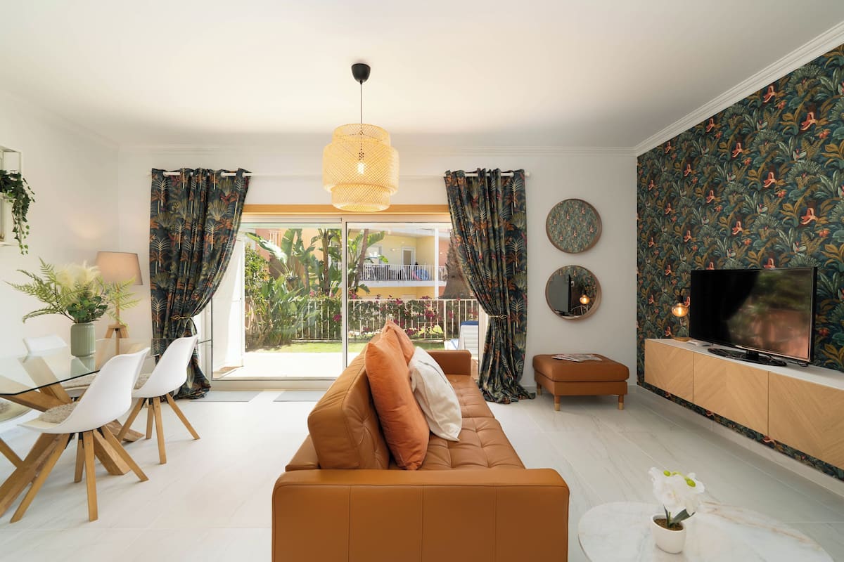 A modern living room with a sofa, TV, and dining area.