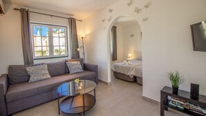 Un salon moderne avec un canapé, une table basse en verre et un téléviseur fixé au mur.