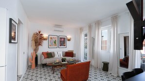 Un salon avec un sol à motifs, un canapé, une table basse et une décoration en forme de cactus.