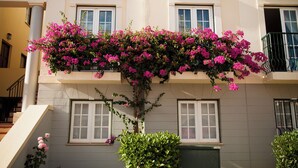 Un bâtiment doté de trois fenêtres, d’un escalier et d’un balcon orné de fleurs roses.