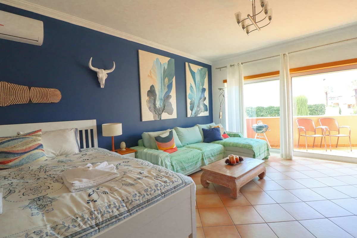 A bedroom with a bed, two sofas, a coffee table, and artwork on the walls.