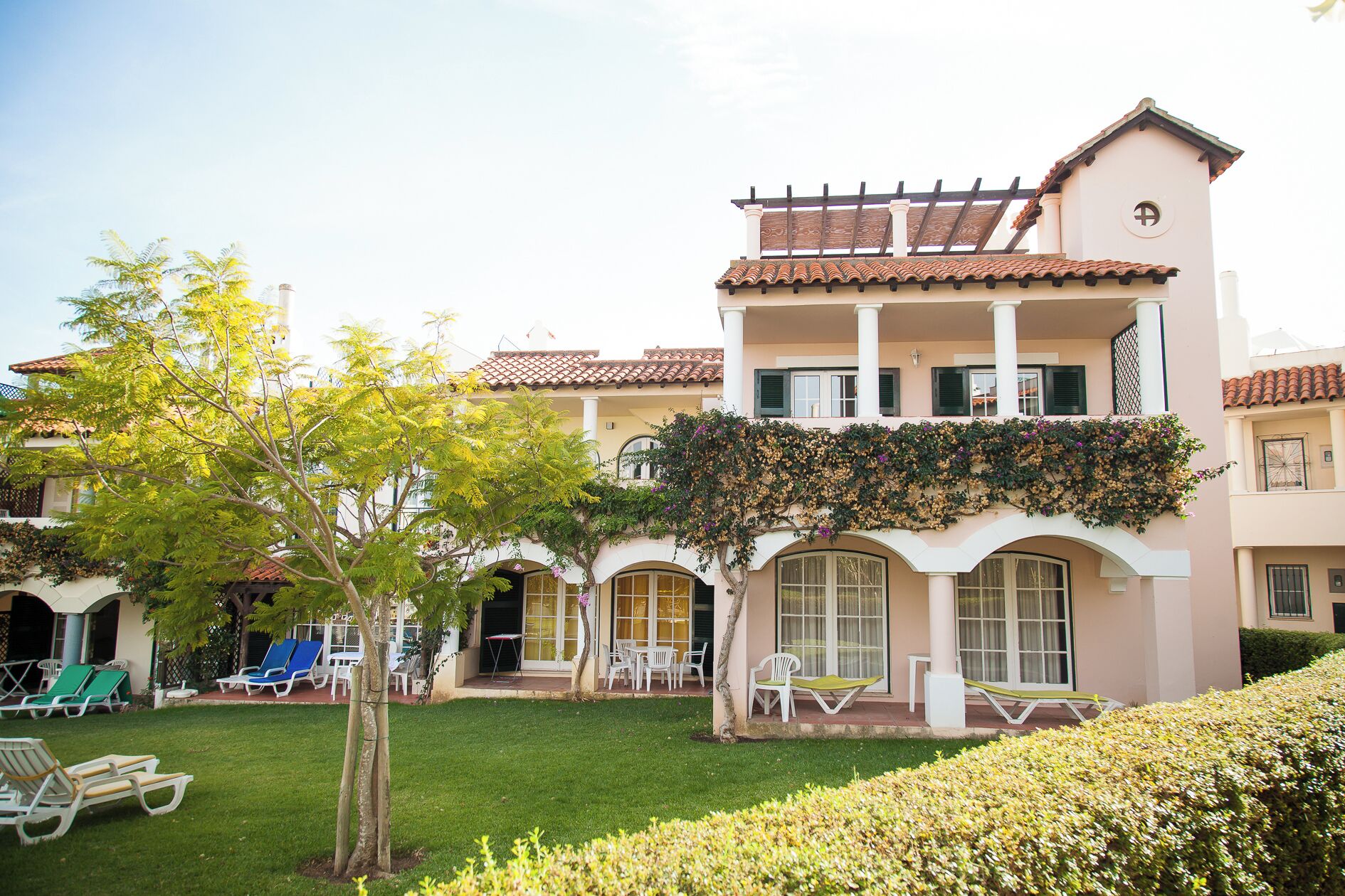 A two-story building with a balcony, outdoor seating, and a well-maintained garden.
