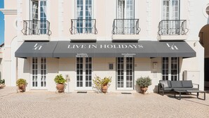 Un immeuble avec une enseigne indiquant « VIVEZ VOS VACANCES » et des plantes en pot devant l’entrée.