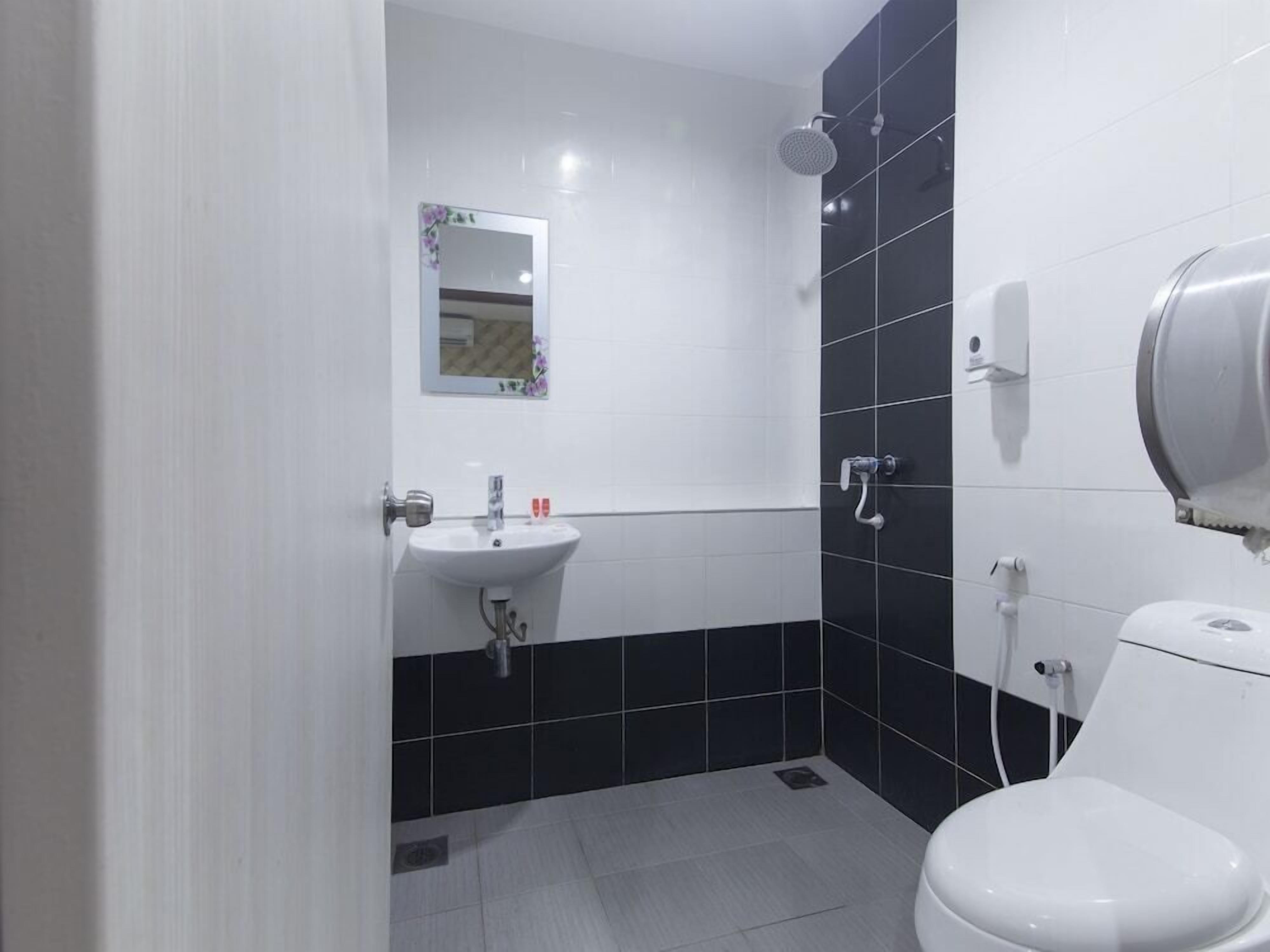 A bathroom with a white sink, black tiled walls, a toilet, and a shower.