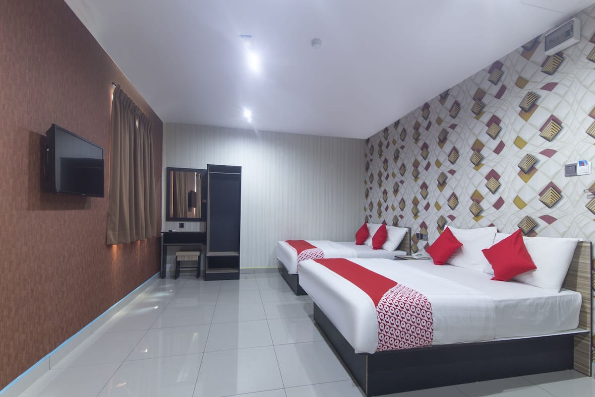Quarto de hotel com cama, escrivaninha, cadeira e televisão.