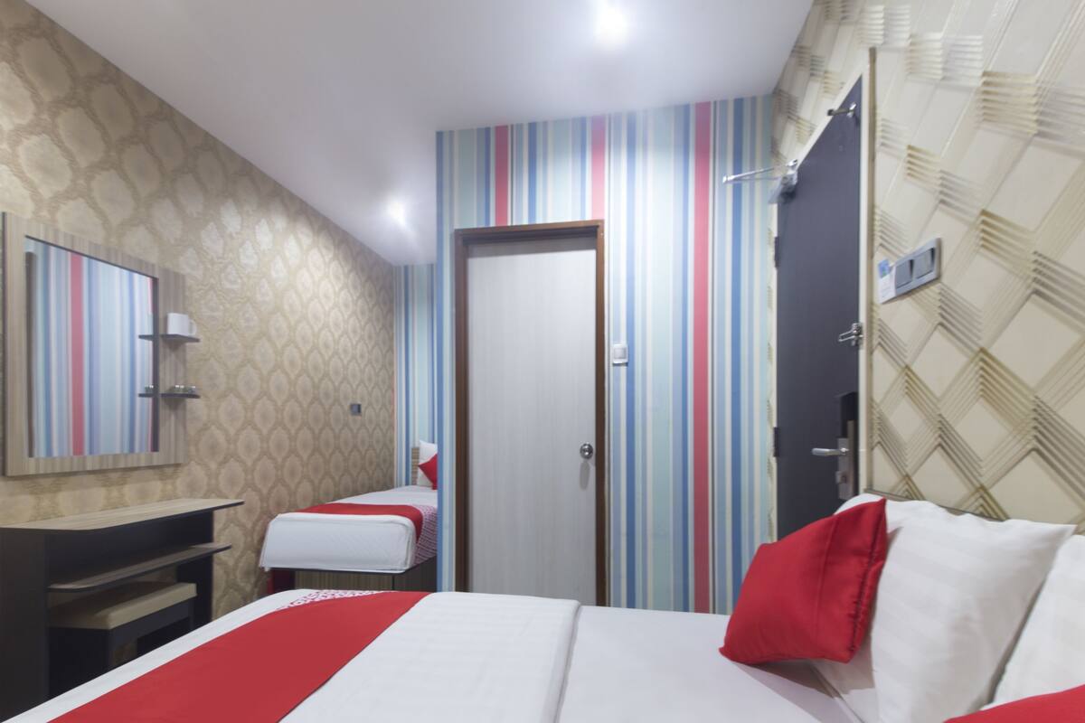 Quarto de hotel com cama, mesa de cabeceira, espelho e porta.