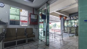 A waiting area with a bench, a clock, and a glass door leading outside. - Super OYO Capital O 804 Hotel Pinji (Ipoh)