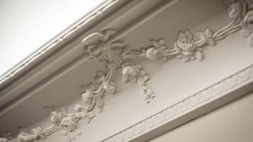 A close-up of a white decorative molding with floral patterns.
