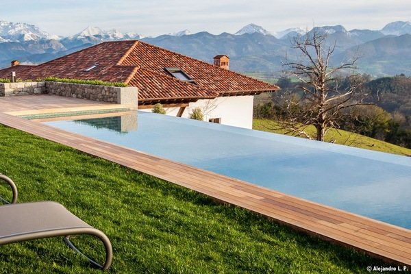 Una piscina al aire libre, sombrillas, sillones reclinables de piscina