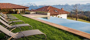 Una piscina al aire libre, sombrillas, sillones reclinables de piscina