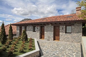 Un edificio de piedra con tejado de tejas, puertas de madera y un patio empedrado.