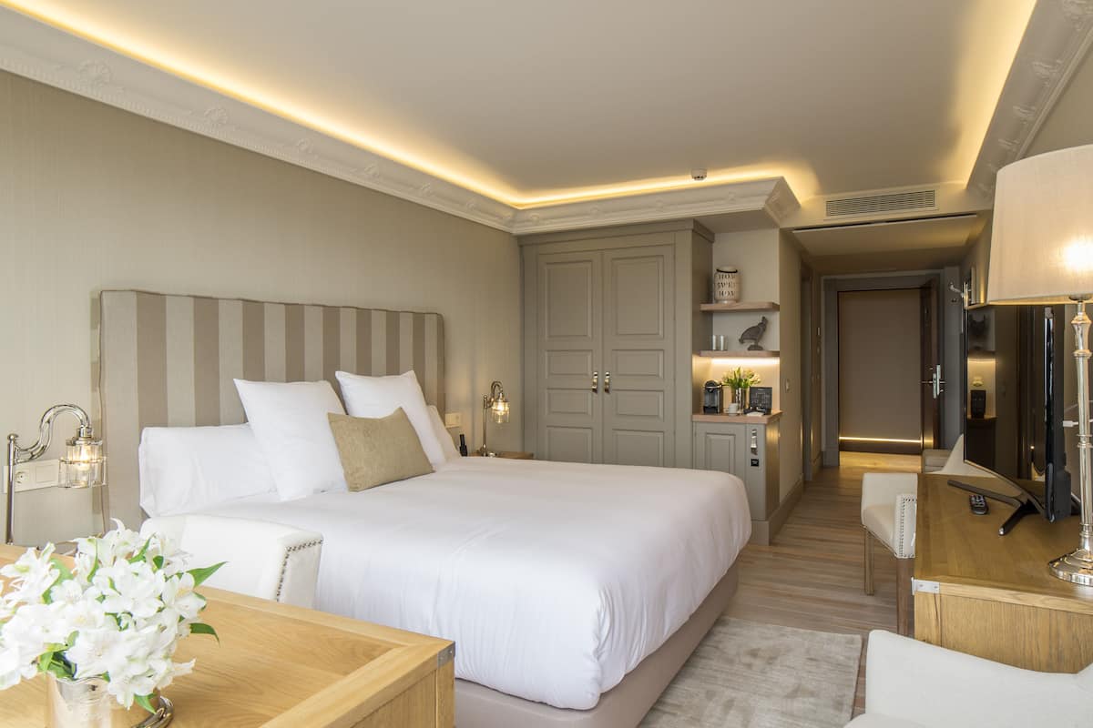 Een hotelkamer met een groot bed, nachtkastjes, een bureau en een spiegel.