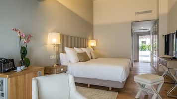 Una habitación de hotel moderna con una cama grande, lámparas de noche, un escritorio con cafetera y una televisión.