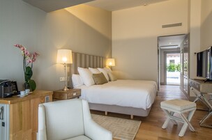 Una habitación de hotel moderna con una cama grande, lámparas de noche, un escritorio con cafetera y una televisión.