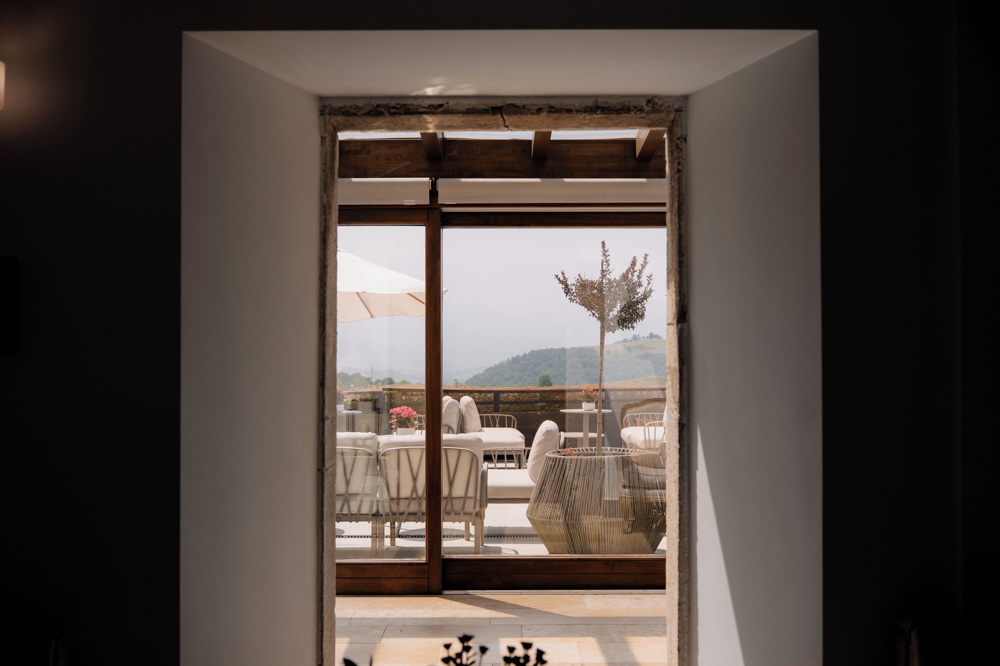 A doorway leading to an outdoor seating area with a view of a mountainous landscape.