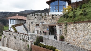 A stone castle-like building with a modern glass extension, stone walls, and a stone staircase leading to the entrance. - Puebloastur Eco-Resort Wellness & Spa (Parres)