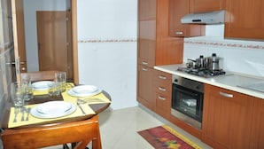 A compact kitchen with wooden cabinets, a gas stove, and a built-in oven. - Miradouro de Gamboa (Praia)