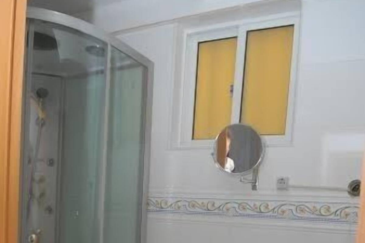 A bathroom with a toilet, a glass-enclosed shower, a sink with a bowl, and a mirror above the sink.
