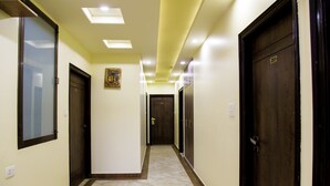 A hotel hallway with doors, a framed picture on the wall, and a tiled floor. - FabHotel Padmavati Palace Mansarovar (Jaipur)