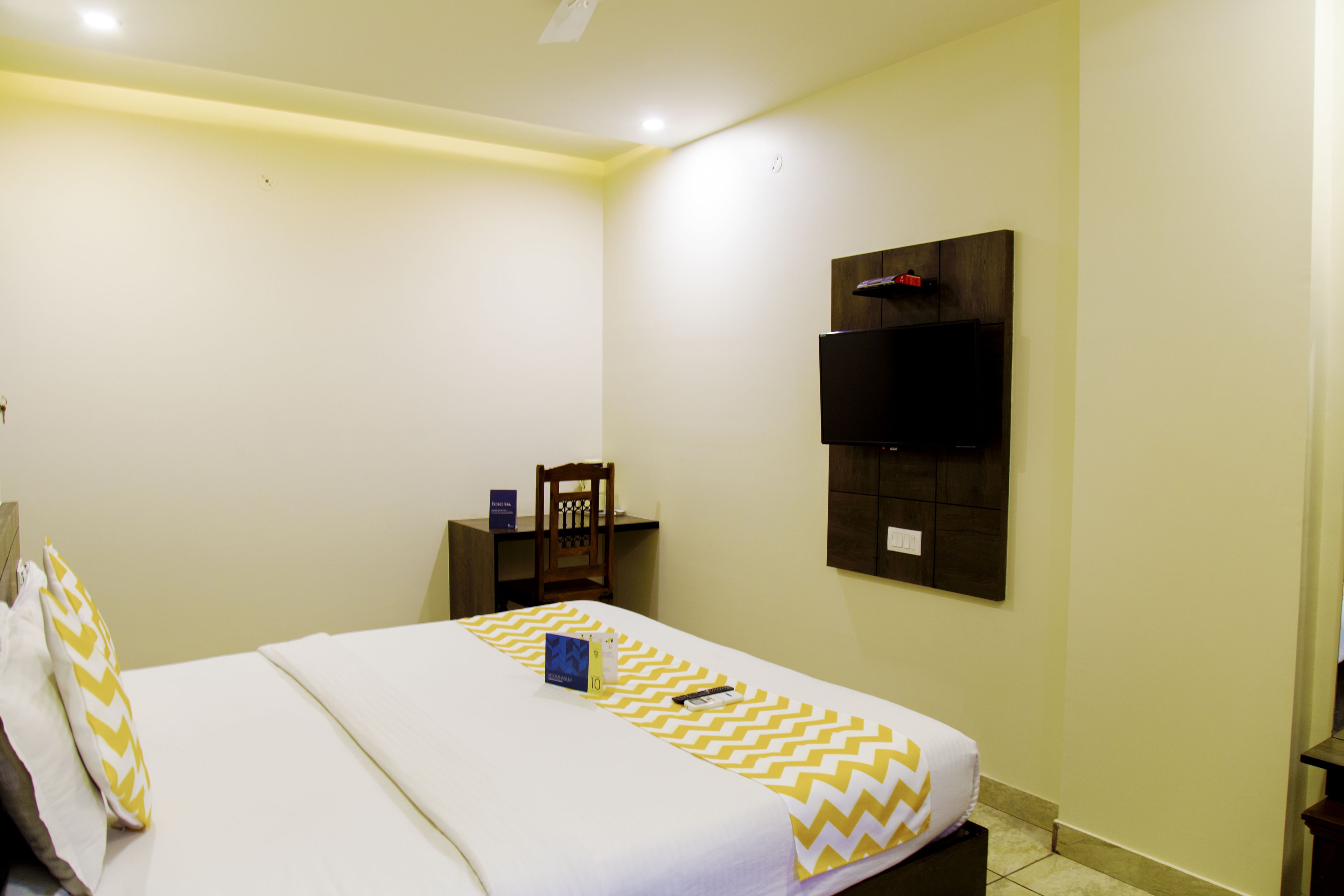 Una camera d'albergo con un letto, una scrivania, una sedia e una televisione a parete.