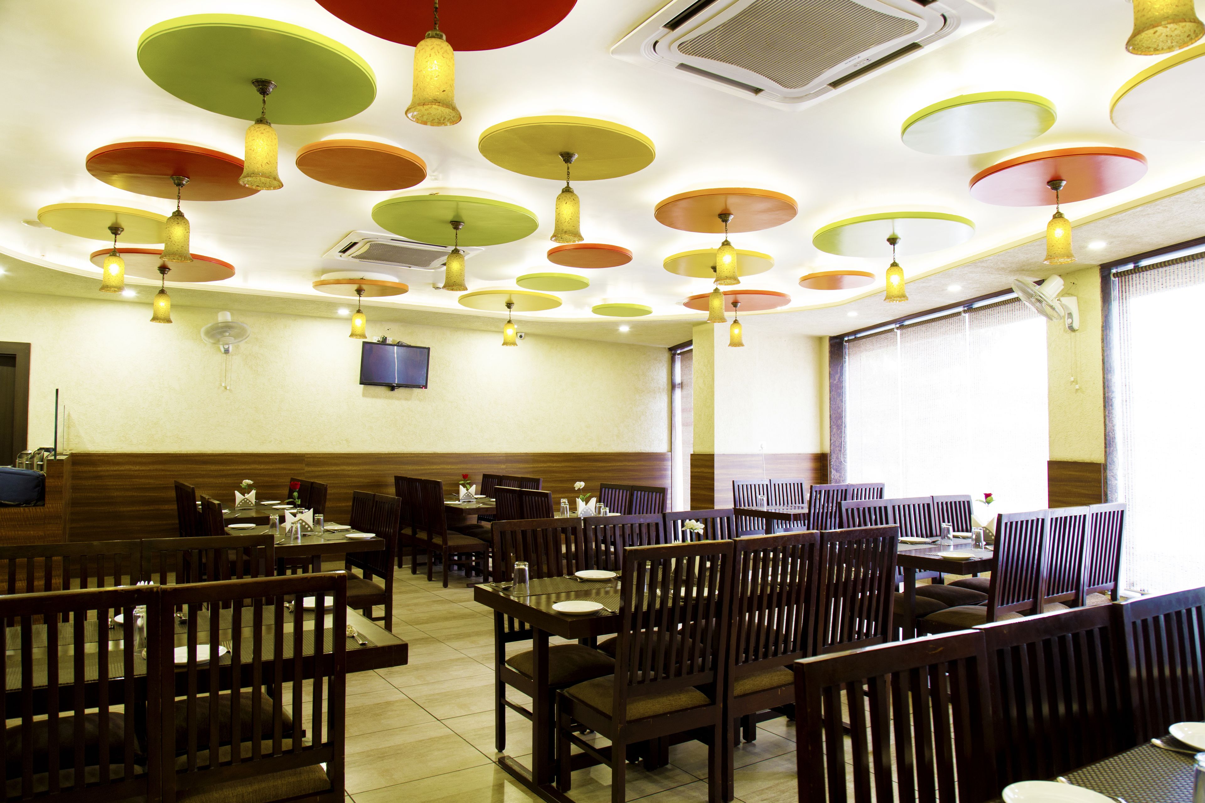 A restaurant with multiple tables and booths, ceiling fans, and a television mounted on the wall.