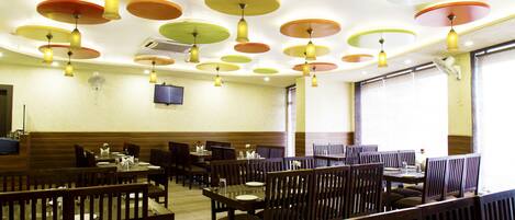 A restaurant with multiple tables and booths, ceiling fans, and a television mounted on the wall.