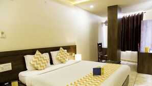 A hotel room with a large bed, wooden headboard, and a nightstand with a phone and a sign. - FabHotel Padmavati Palace Mansarovar (Jaipur)