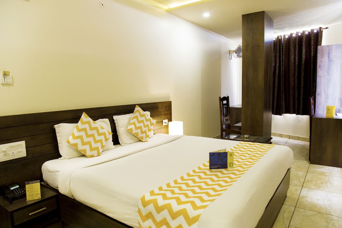 A hotel room with a large bed, wooden headboard, and a nightstand with a phone and a sign.
