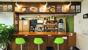 Eine Theke in einem Restaurant mit einer Speisekarte, Barhocker und einer Kaffeemaschine.
