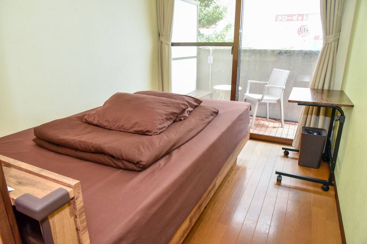 Een kamer met een bed, een klein tafeltje en een stoel.