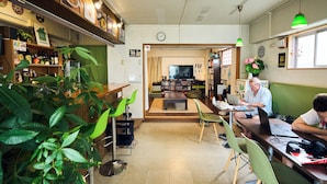 Ein gemütliches Café mit Holztresen, grünen Stühlen und einem Fernseher im Hintergrund.