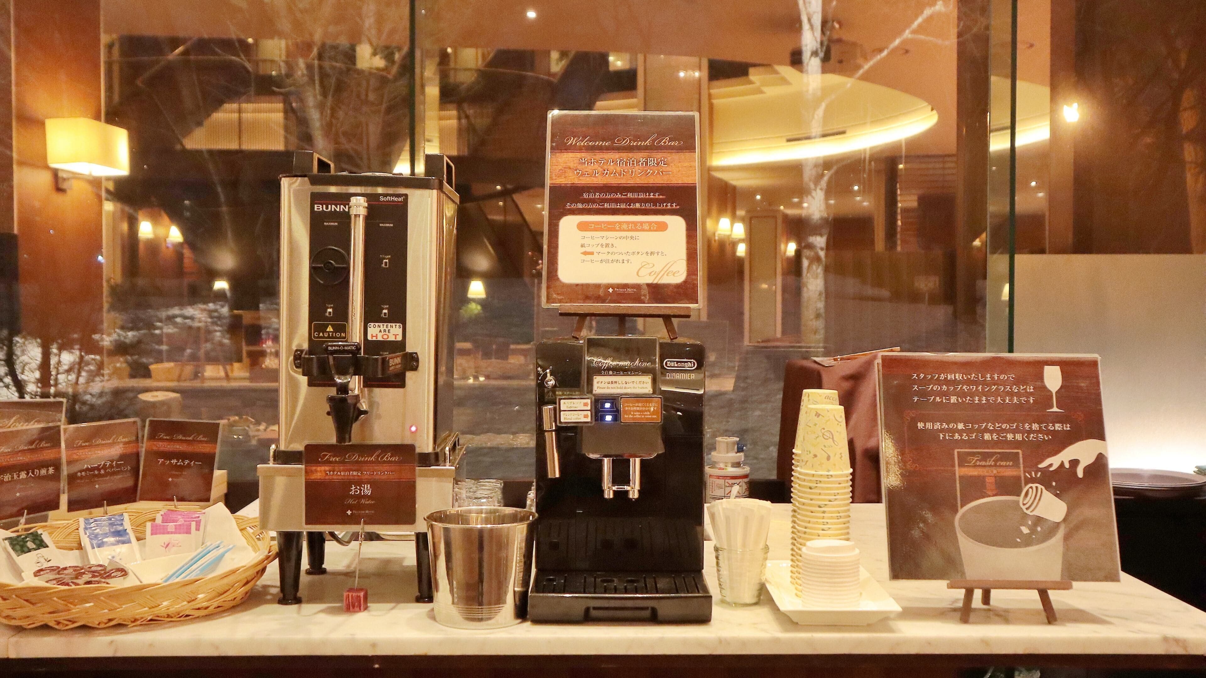 A coffee machine, a drink bar sign, and a stack of disposable cups.