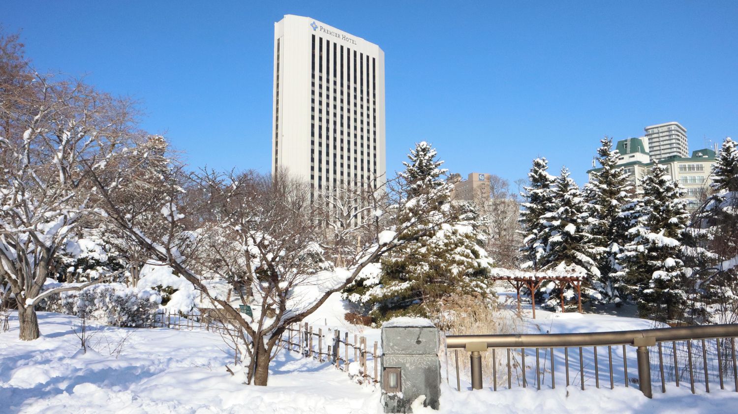 Ein mit Schnee bedeckter Park mit einem hohen Gebäude im Hintergrund.