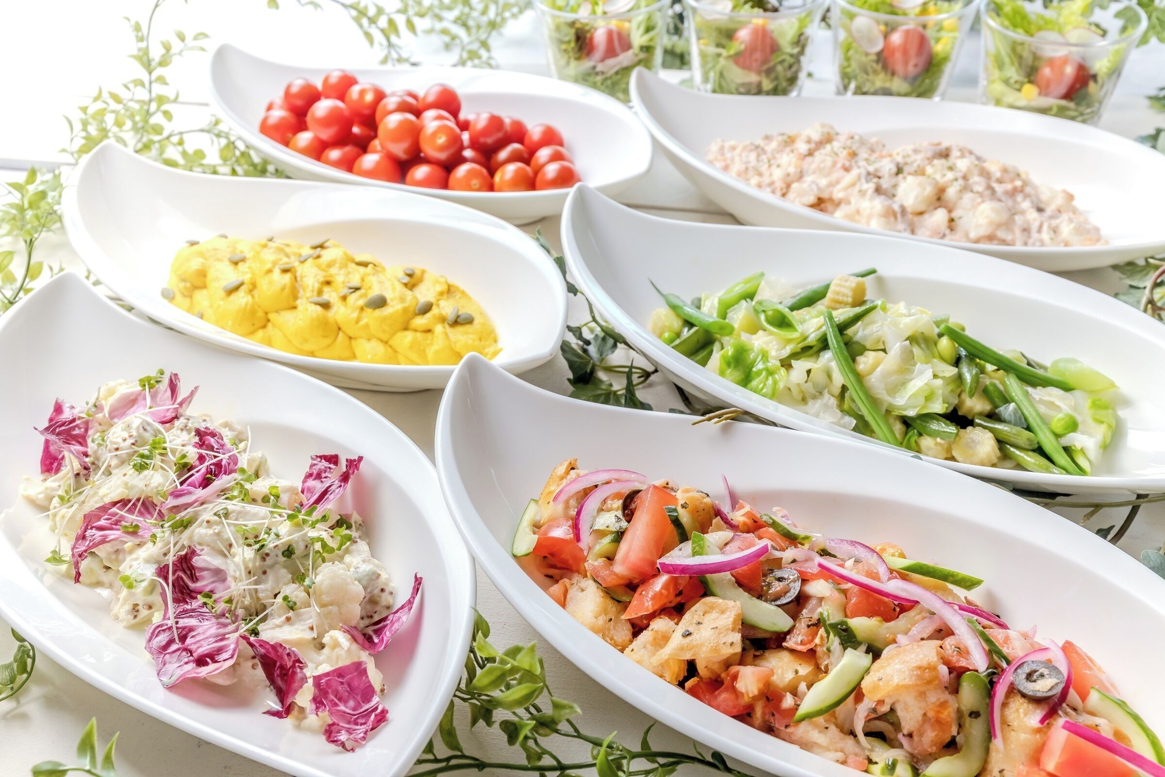 A variety of dishes on white oval plates, including salads and a dish with cauliflower.