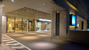 L’entrée d’un hôtel avec une façade en verre, un comptoir d’accueil et un sol carrelé.