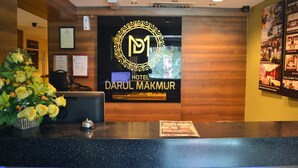 Un mostrador de recepción de hotel con un logotipo, un certificado enmarcado y un arreglo floral.