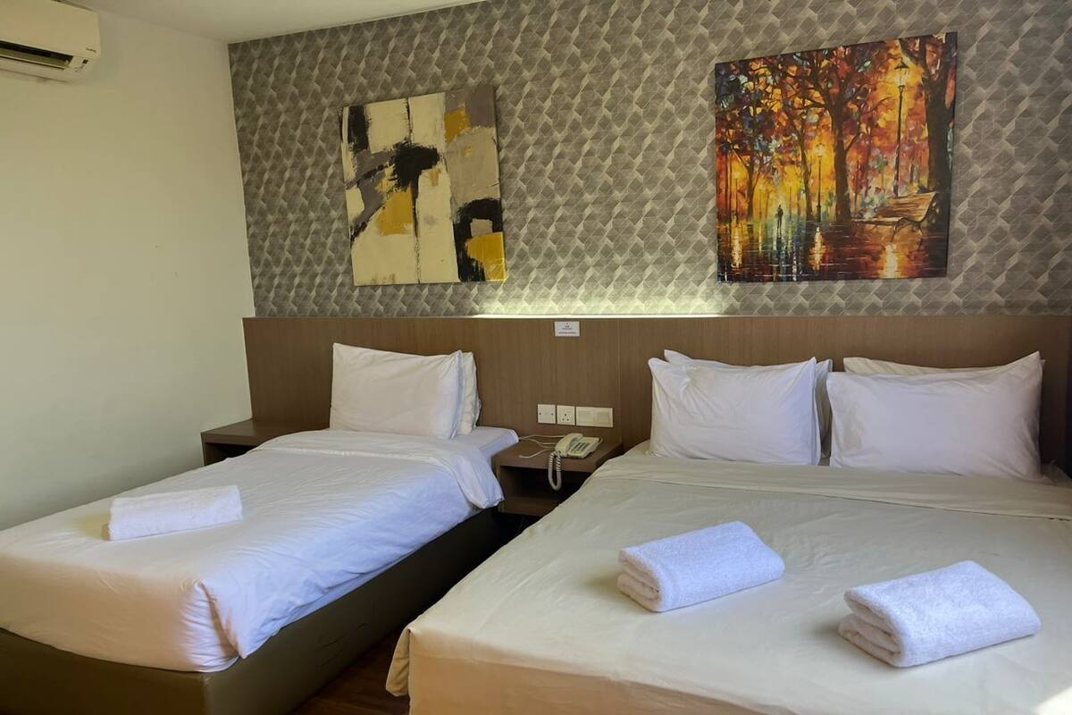 A hotel room with two beds, a painting on the wall, and a telephone on the nightstand.