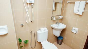 A bathroom with a toilet, sink, mirror, towel rack, and a trash bin.
