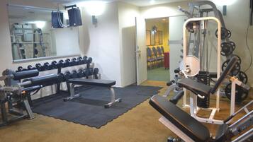 A gym with exercise equipment, a mirror, and a door leading to another room.