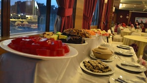 Una mesa de buffet con diversos platos y vistas de la ciudad a través de amplias ventanas.