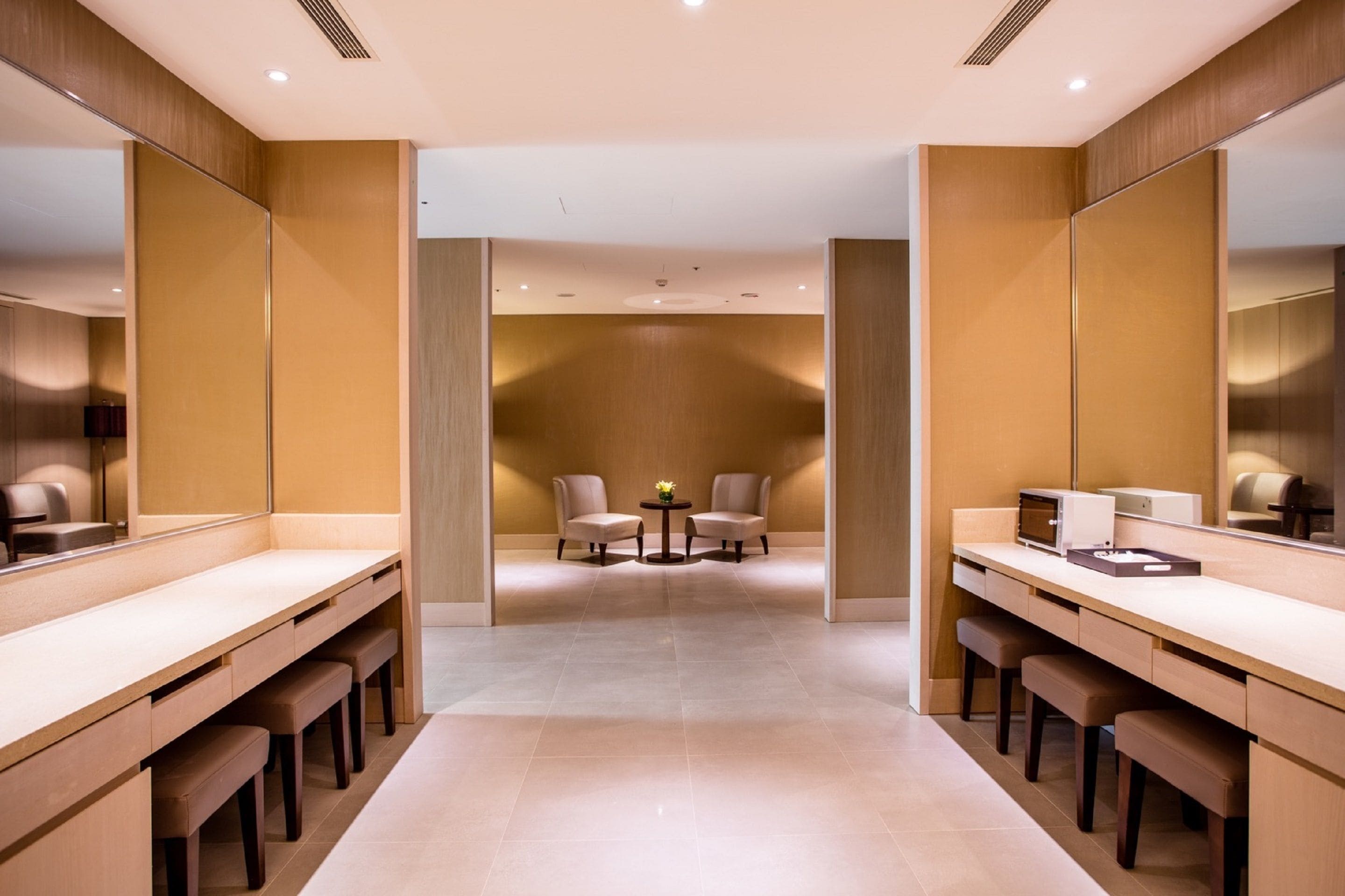 Een moderne badkamer met twee wasbakken, bankjes en een klein tafeltje met stoelen.