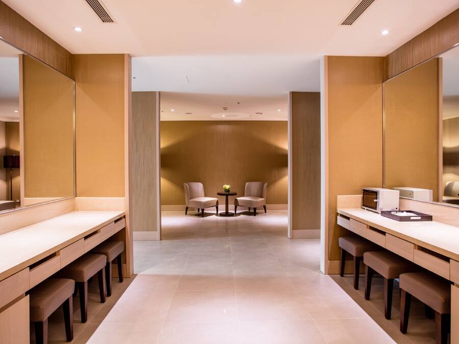 Een moderne badkamer met twee wasbakken, bankjes en een klein tafeltje met stoelen.