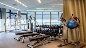 A modern gym with various exercise equipment, large windows, and a view of the city. - Fullon Hotel Taoyuan Airport Access MRT A8 (Taoyuan City)