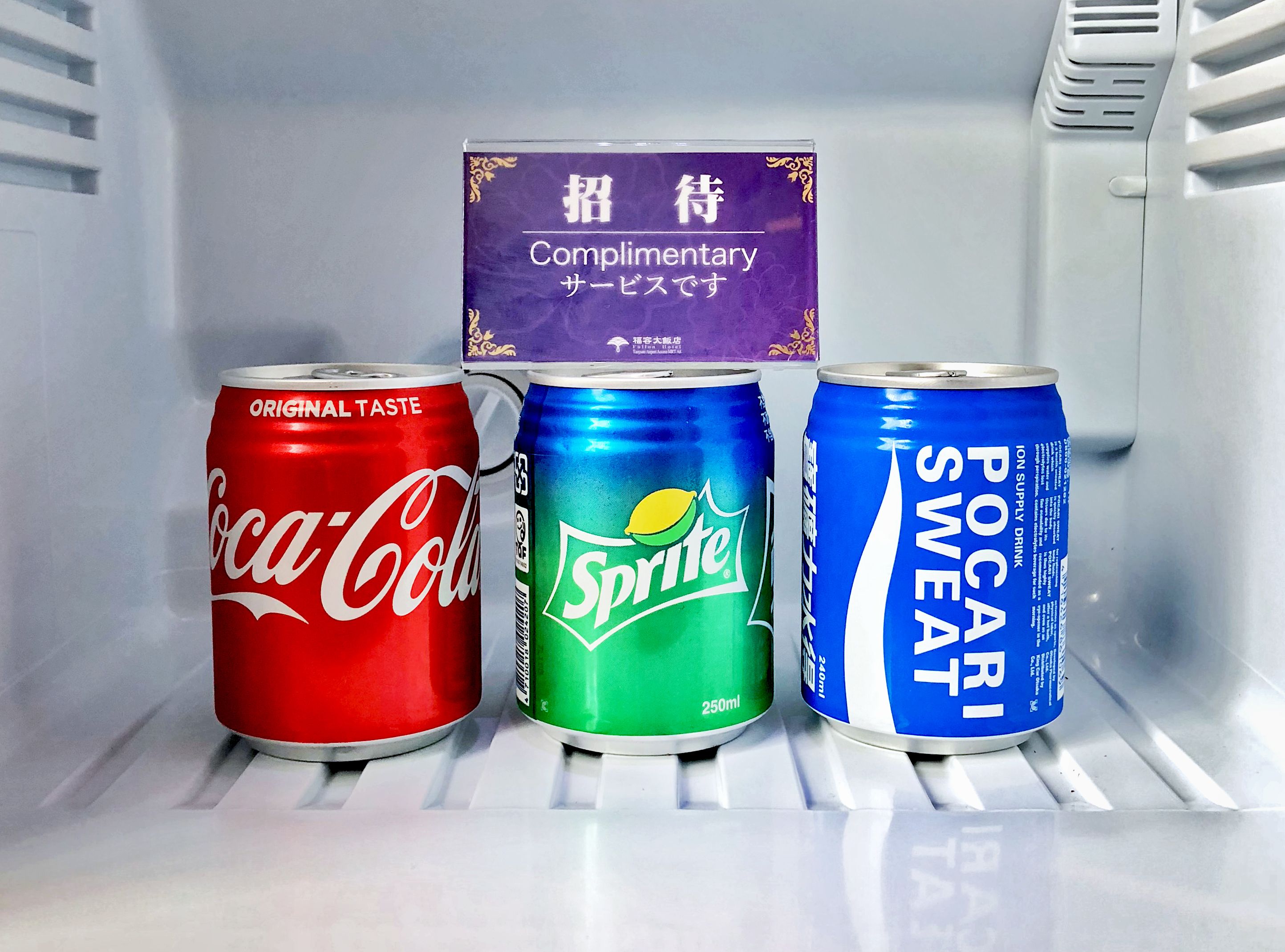 Three beverage cans in a refrigerator.