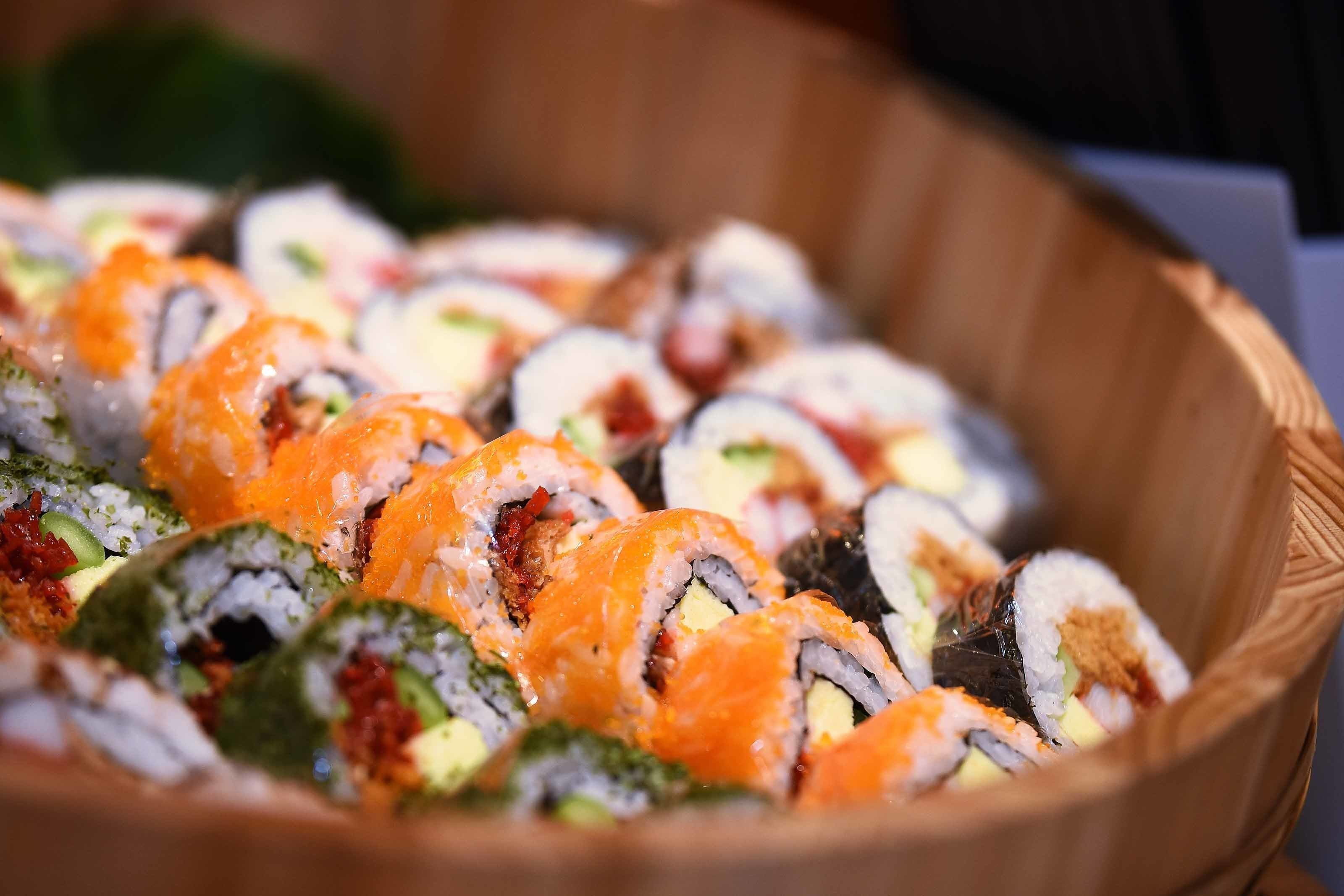 Uma cesta de madeira cheia de diferentes tipos de sushi.