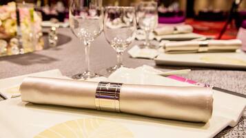 A table set with white plates, folded napkins, and clear wine glasses.