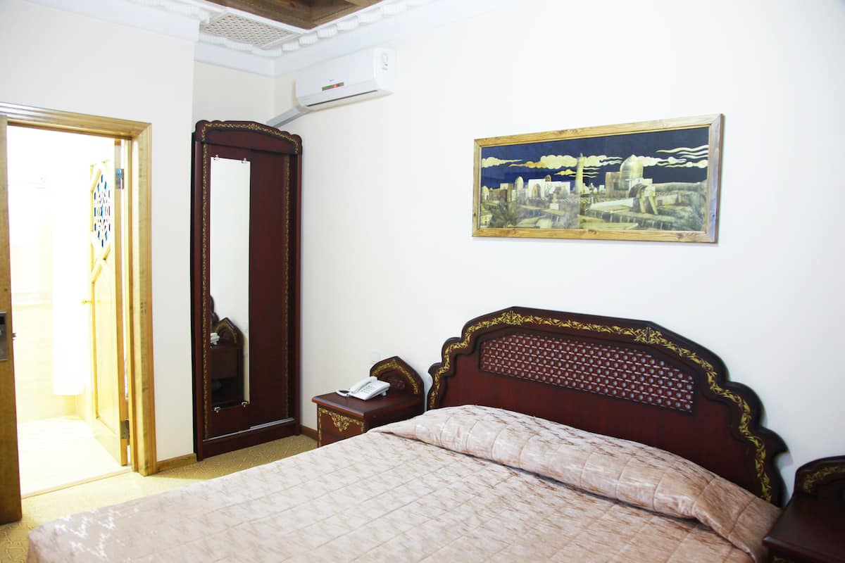 Ein Schlafzimmer mit einem hölzernen Bett, einem Nachttisch, einem Spiegel und einem Bild an der Wand.