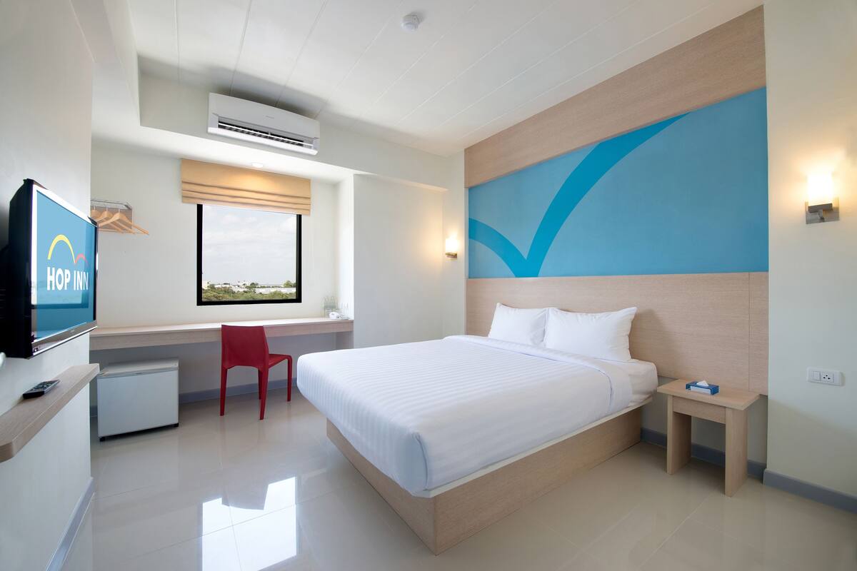Ein modernes Hotelzimmer mit Bett, Schreibtisch, Fernseher und einem Fenster mit Blick.